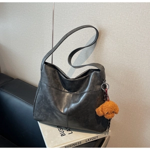 Detail of dark grey distressed faux leather tote bag with a brown plush puppy charm