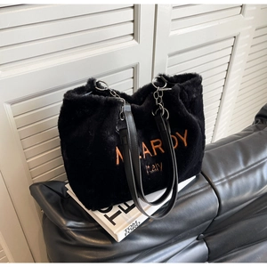 Detail of plush black tote bag with orange MLARDY embroidery and metal chain strap