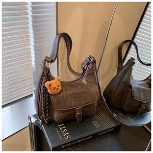 Détail d'un sac sous les aisselles en cuir marron vintage avec breloque ours et reflet miroir