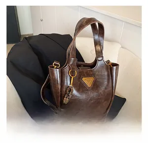Detail of vintage coffee brown bucket bag with tassel and triangle metal emblem
