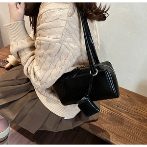 Detail of black leather rectangle shoulder bag with mini pouch on beige sweater