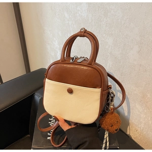 Close-up of a two-tone mini handbag in brown and cream PU leather with bear charm
