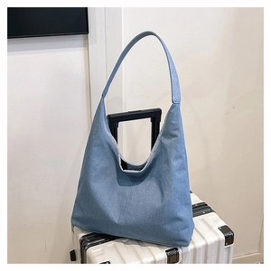 Détail de la texture d'un sac cabas en denim bleu avec fermeture magnétique