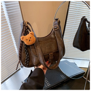 Détail du sac hobo vintage en cuir marron avec breloque ours et cordon tressé