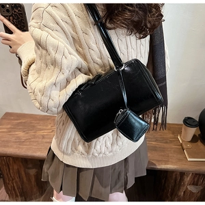 Detail of black patent leather baguette bag with detachable coin purse on beige sweater
