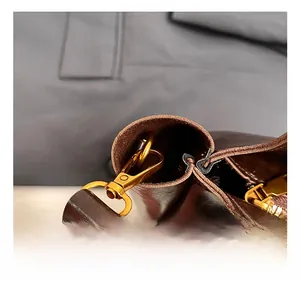 Detailed close-up of premium golden metal hook and brown leather strap on retro bucket bag