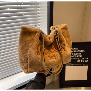 Detailed close-up of brown plush tote bag featuring embroidered lettering and leather handles