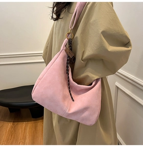 Close-up of pink suede tote bag detail with unique metal charm and woven drawstring
