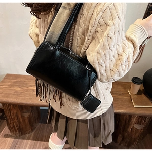 Detail of a black matte leather underarm bag with a matching small coin purse pendant