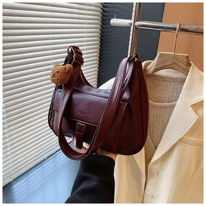Détail du sac demi-lune bordeaux avec breloque ours et poche à boucle élégante