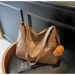 Brown large tote bag in matte faux leather with a cute plush bear charm on a chair