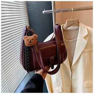 Détail du sac à bandoulière vintage bordeaux avec charm ours en peluche et sangle