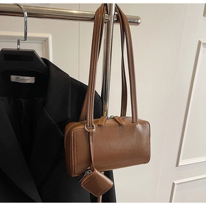 Detail of vintage brown PU leather shoulder bag with a matching mini pouch charm accessory