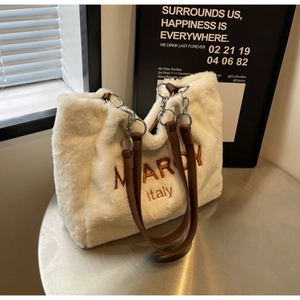 Detailed close-up of white plush tote bag featuring orange MARON embroidery and leather strap