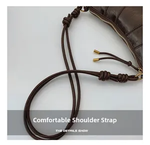 Detail of dark coffee leather shoulder bag featuring knotted rope strap and gold hardware