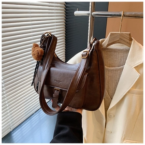 Détail du sac à bandoulière marron vintage avec boucle métal et breloque ourson