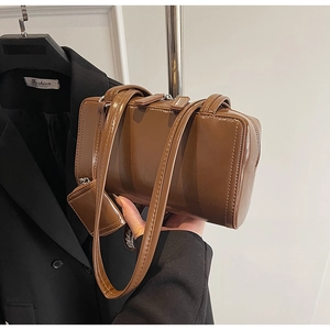 Detail of a dark brown glossy leather underarm bag with a matching hanging coin purse