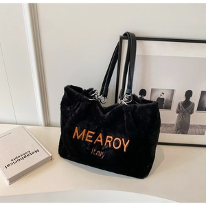 Detail of black faux fur tote bag featuring orange embroidered text and leather handles