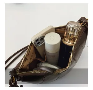 Detailed interior of dark brown leather dumpling bag showing capacity and gold zipper