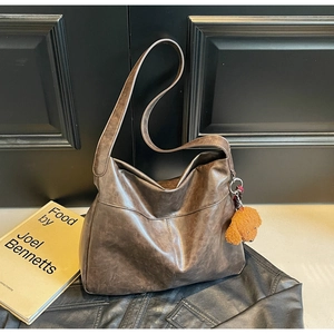Detail of a dark brown vintage hobo tote bag with a cute plush dog charm and soft leather