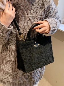 Large black plush tote bag with gold metal buckle and adjustable faux leather shoulder strap