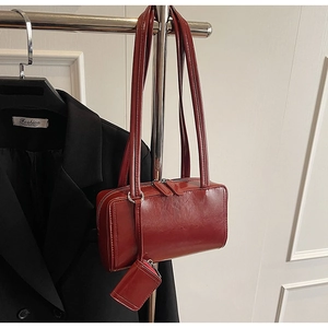 Detail of burgundy glossy tote bag with dual shoulder straps and matching mini coin purse
