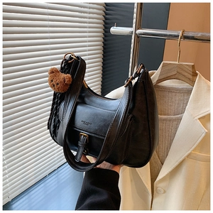 Détail d'un sac à bandoulière vintage demi-lune noir avec un joli petit ours en peluche