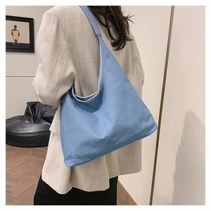 Sac fourre-tout hobo en jean bleu clair porté par un modèle avec un style minimaliste