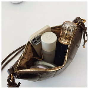 Interior view of brown leather bag showing spacious storage for phone and cosmetics