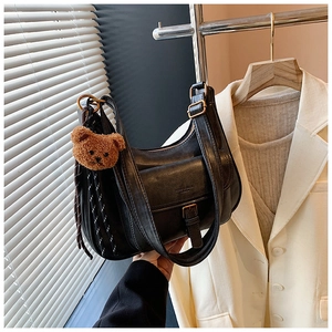 Détail d'un sac hobo noir vintage avec charm ours en peluche et ruban rayé