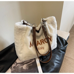 Close-up of white plush tote bag with brown Marcy Italy embroidery and leather handles