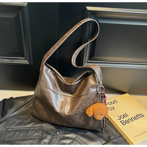 Detail of vintage brown tote bag with leather texture and plush puppy accessory