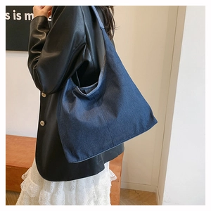 Détail du grand sac cabas en denim bleu foncé porté par un mannequin pour le quotidien