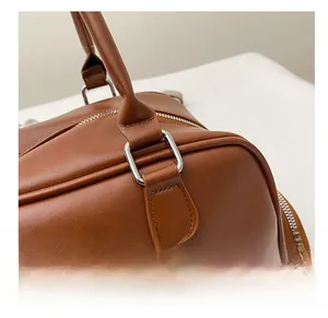 Detailed close-up of brown leather bag showing silver metal ring and fine stitching detail