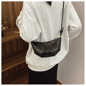 Detail shot of black croissant dumpling bag with signature layered pleats and knotted strap