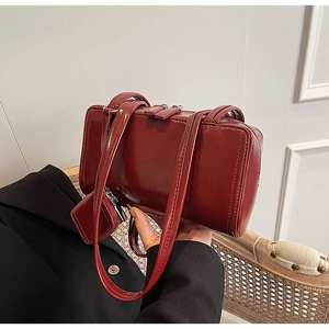 Close-up of deep red glossy underarm bag with double zipper and silver hardware