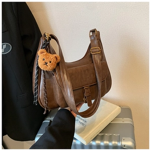 Sac à bandoulière vintage marron avec charm ours et ruban dans un décor lifestyle