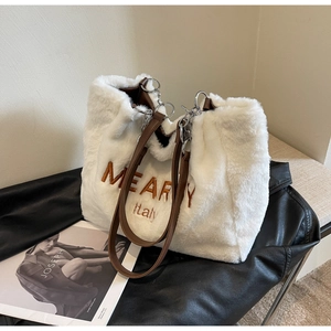 Detailed texture of white plush tote bag with brown embroidery on black leather jacket