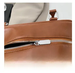 Close-up of smooth silver metal zipper and neat stitching on a brown leather bag