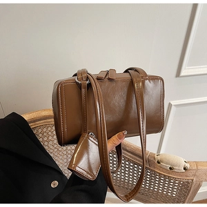 Close-up of a glossy dark brown shoulder bag with a matching mini detachable coin purse