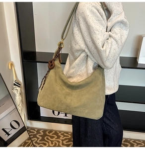 Detail of olive green suede hobo bag with gold metal buckles and brown pretzel charm