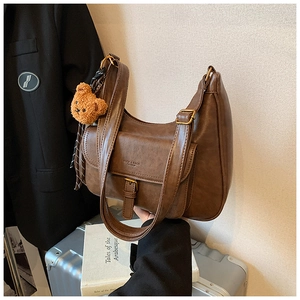 Détail du sac à bandoulière vintage marron foncé avec sangle et breloque ours mignon