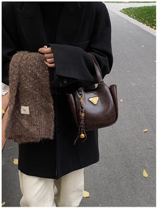 Outdoor shot of a vintage brown leather bucket bag styled with a warm winter scarf