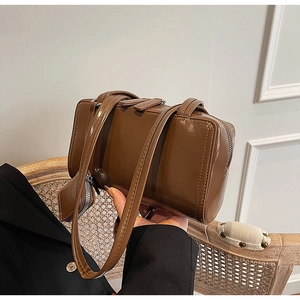 Detail of vintage brown patent leather shoulder bag on a rattan chair in soft lighting