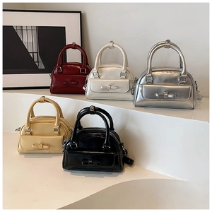 Detailed view of glossy Boston bags in five colors with bow-tie decorative front pockets