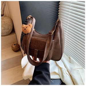 Détail d'un sac demi-lune marron avec poche à pression et pendentif ours mignon