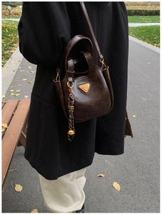 Detailed macro view of dark brown retro bucket bag with metallic logo and charm