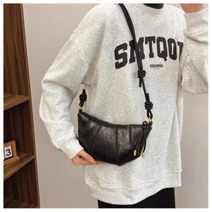 Detail of black crescent crossbody bag in glossy oil wax leather with decorative knot