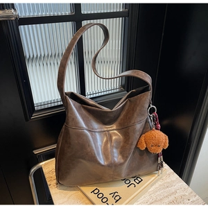 Macro view of coffee brown faux leather tote with brown teddy dog plush charm