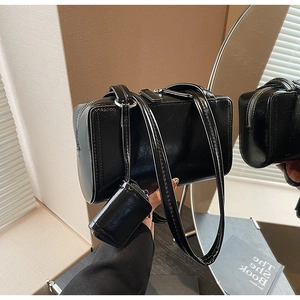Detail of black glossy shoulder bag with silver zipper and mini detachable pouch charm